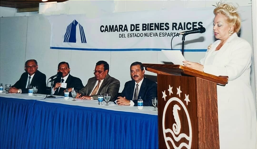 Doris Perozo hablando desde el podio ante el pendón de la Cámara de Bienes Raíces del Estado Nueva Esparta