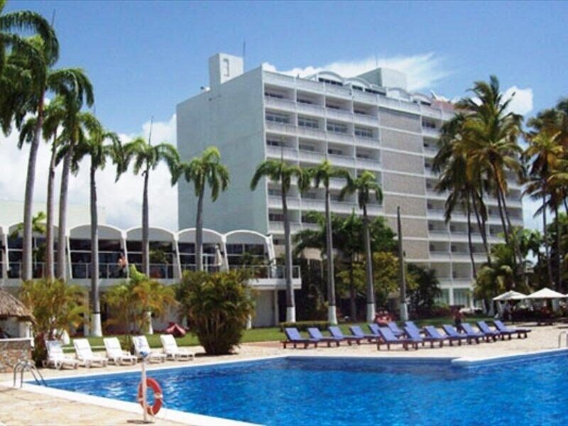 La piscina del Hotel Bella Vista con sus tumbonas y el edificio al fondo