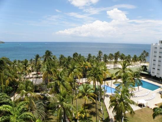 Vista desde una habitación alta del Bella Vista: el jardín de palmeras, la piscina y el Caribe