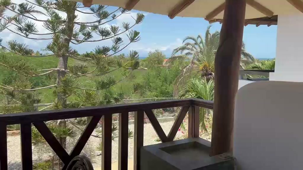 Terraza cubierta con baranda de madera y el mar al fondo
