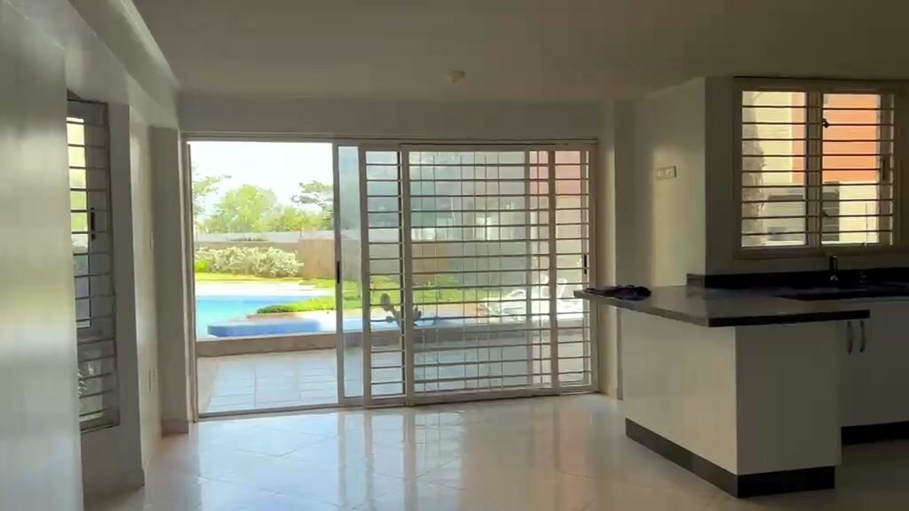 El salón y la cocina, con el ventanal a la terraza y la piscina detrás