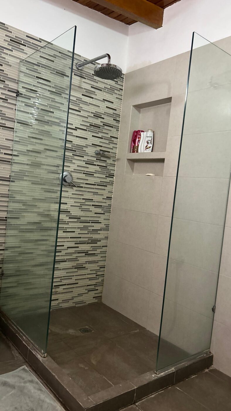 Una de las duchas, con mampara de vidrio