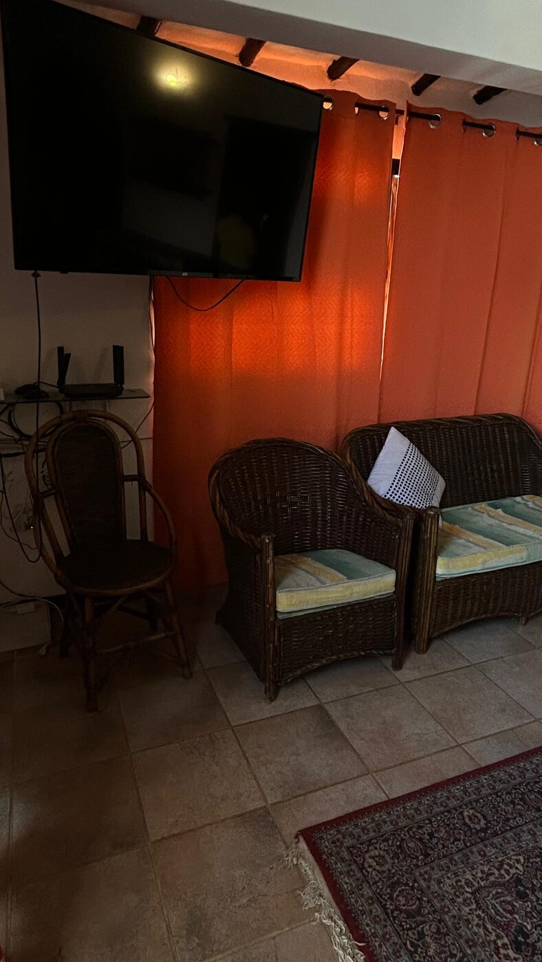 Otra sala, con televisor y muebles de mimbre