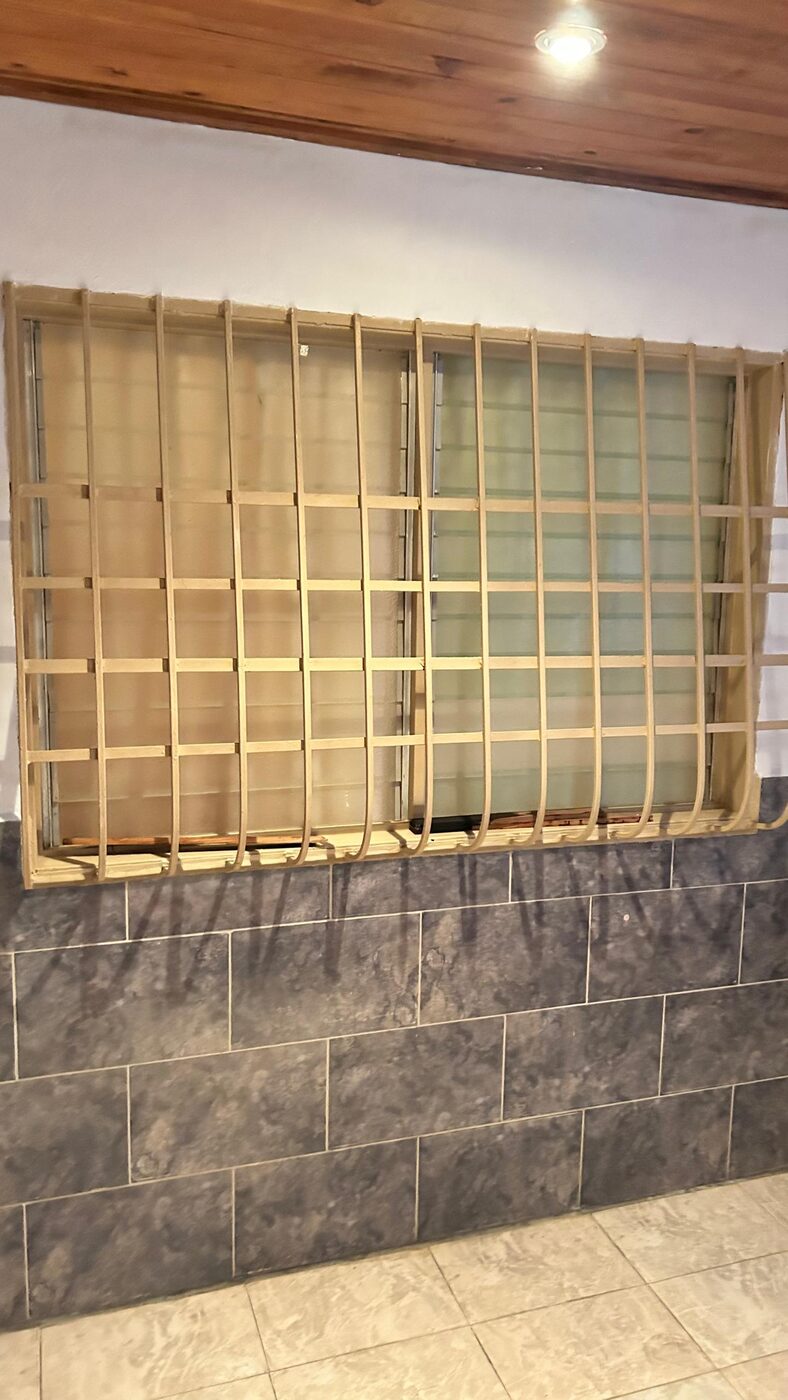Una ventana con su reja de madera