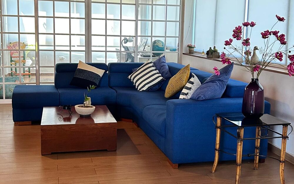 La sala del penthouse de Playa El Agua, con el sofá azul y los ventanales